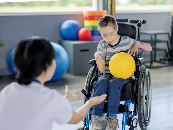 A young boy with cerebral palsy doing physical therapy exercises with his therapist.