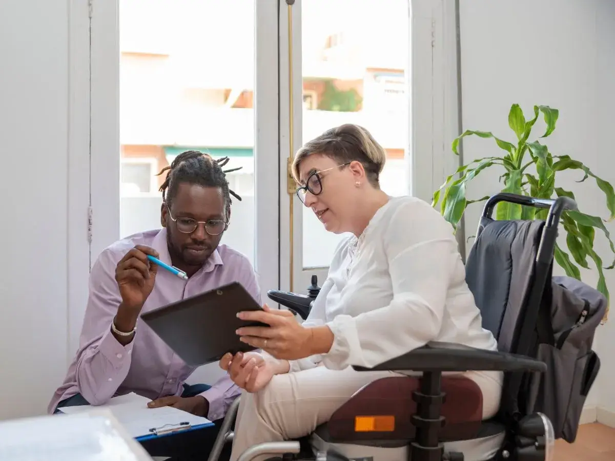 A healthcare professional talks with wheelchair user during an appointment.
