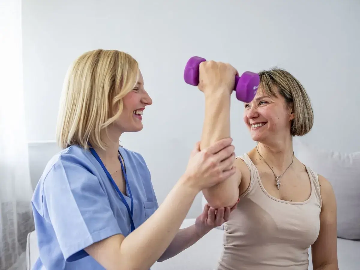 Female allied health worker supports her client to exercise