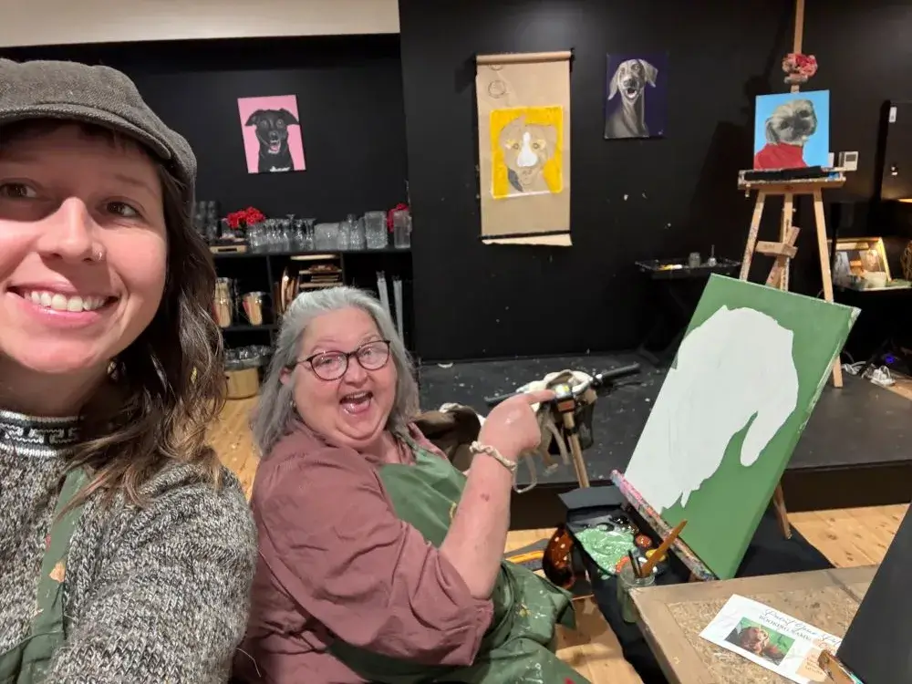 Support worker Chez painting and smiling with her client Corinna