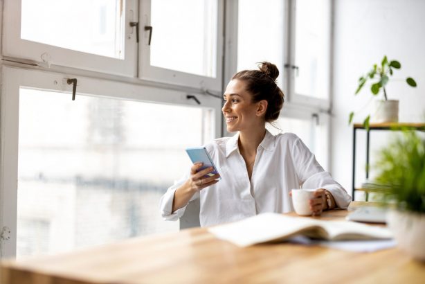 Woman on her phone with a cup of coffee.