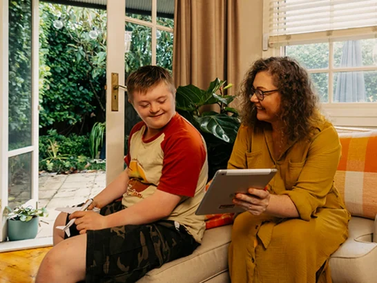 Mum shows son with disability Mable support workers on her tablet.