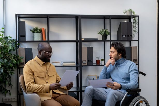 Man using a wheelchair talking with his support worker.