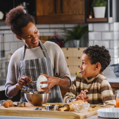 A young boy and his support worker cooking in the kitchen.