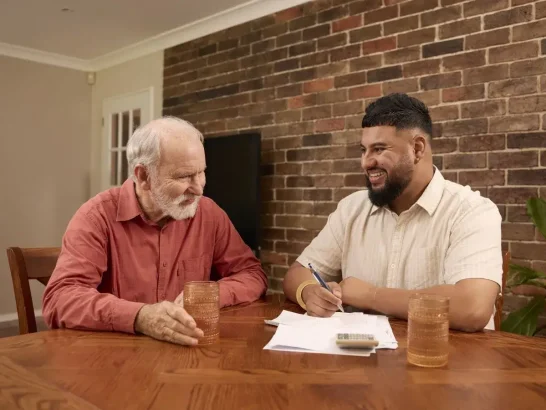 Mable client Dave and his independent support worker talk around a table