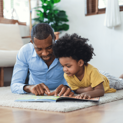 A father and his young son reading a book together.