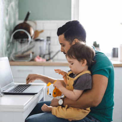 father-working-on-laptop-with-toddler-sitting-on-his-lap-playing-with-stuffed-animal