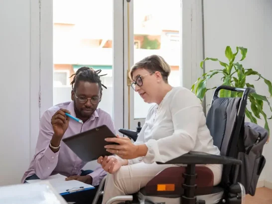 A healthcare professional talks with wheelchair user during an appointment.