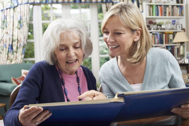 An older women looks at a photo album with her support worker.
