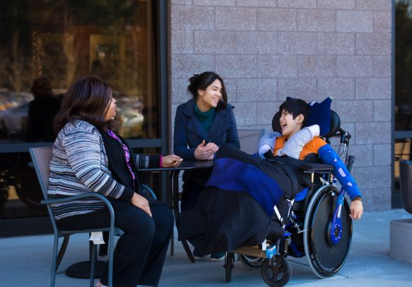 Young boy who uses a wheelchair speaking with his team of support workers.