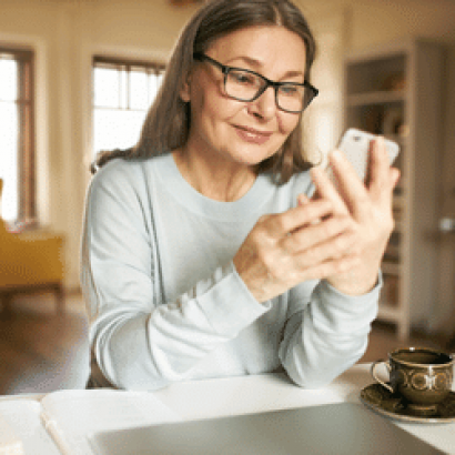 A woman sitting down and looking at her phone.