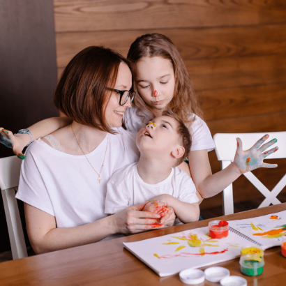 A mother painting with her daughter and her son with cerebral palsy.