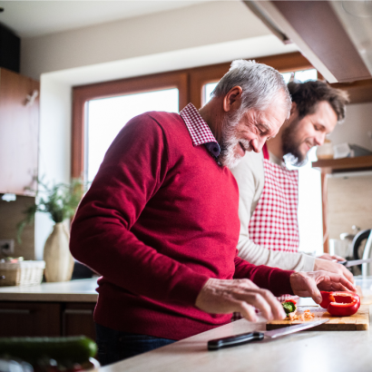 An older man and his support worker chopping vegetables in the kitchen.