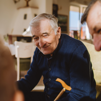 senior man sitting in chair with his family