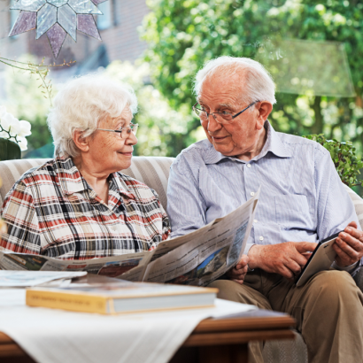 An older couple reading the paper outside together.