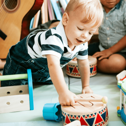 A little boy plays with a drum.