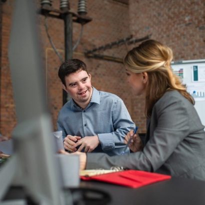 Two coworkers talking in an office.